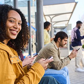 Woman sitting at a bus stop, looking at the camera.